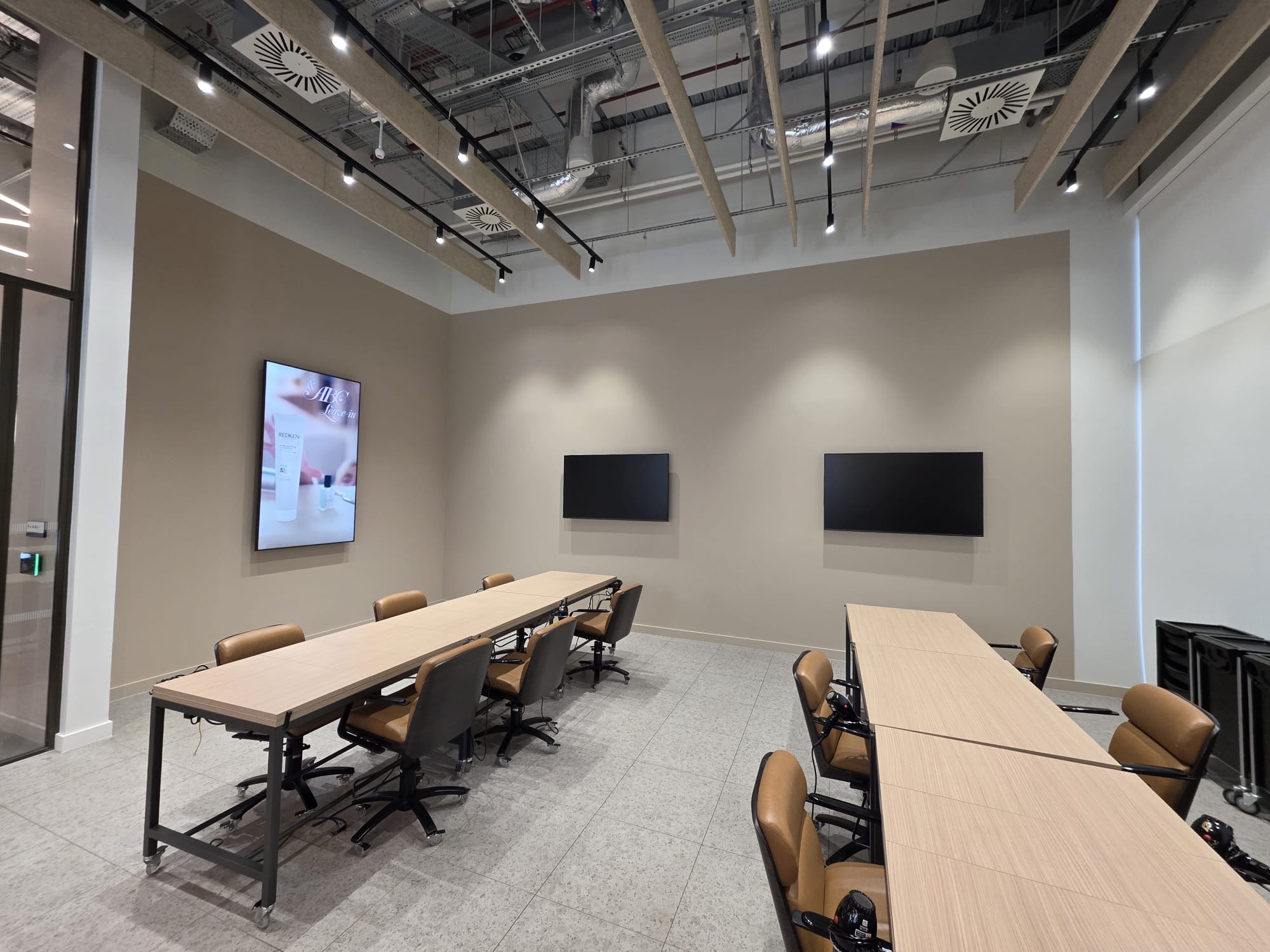 Completed commercial training academy fit-out with folding tables, leather chairs and wall-mounted screens