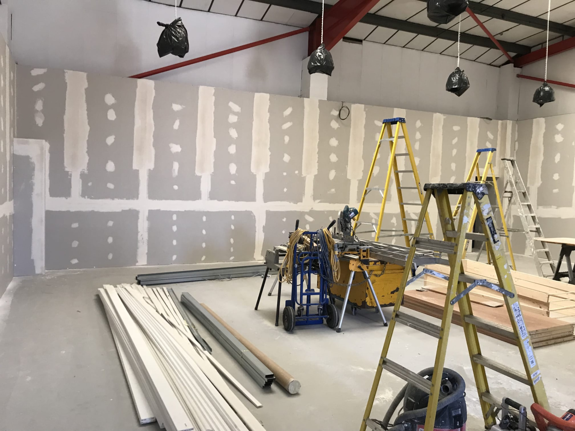 Commercial interior fit-out in progress with freshly plastered partition walls, timber and site equipment
