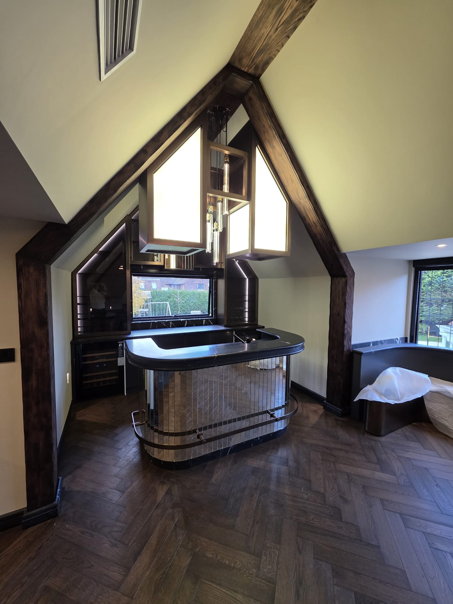 Dark stained oak herringbone flooring laid in a vaulted room with exposed timber beams